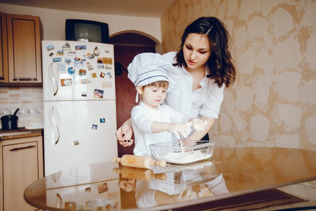 그녀의 작은 딸과 함께 아름다운 젊은 어머니는 집에서 부엌에서 요리입니다