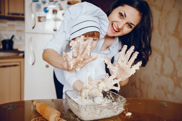 A beautiful young mother with her little daughter is cooking in the kitchen at home