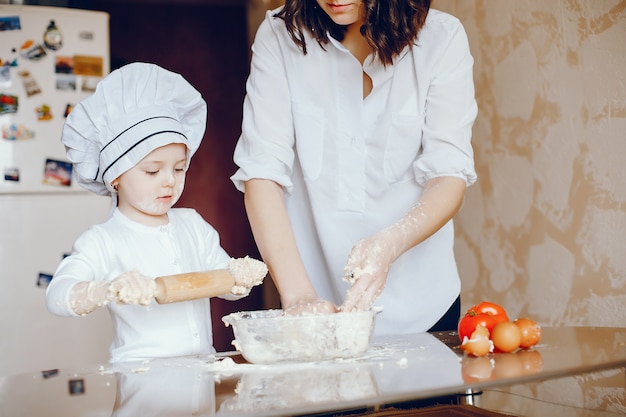 Una bella giovane madre con la sua piccola figlia sta cucinando nella cucina a casa