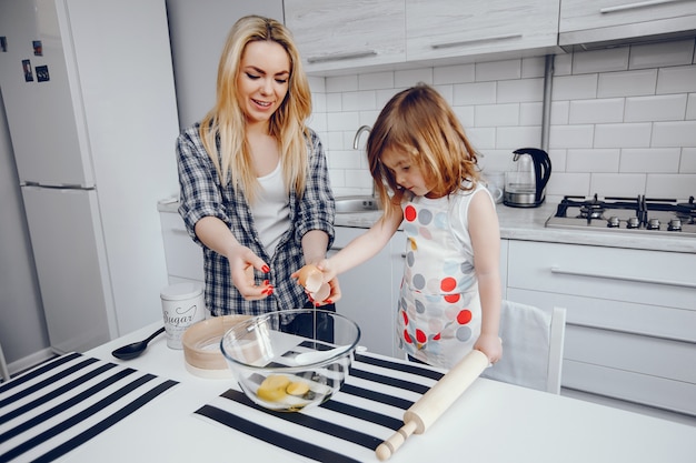 Красивая молодая мать с маленькой дочкой готовит на кухне дома