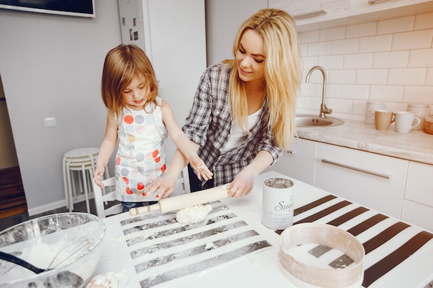 Una bella giovane madre con la sua piccola figlia sta cucinando nella cucina a casa