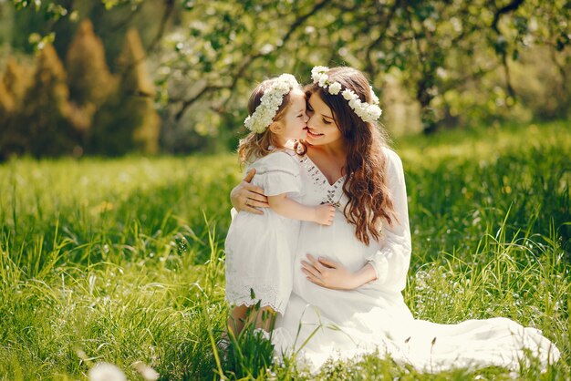 小さな女の子と遊んで長い白いドレスで美しい若い妊娠中の女の子
