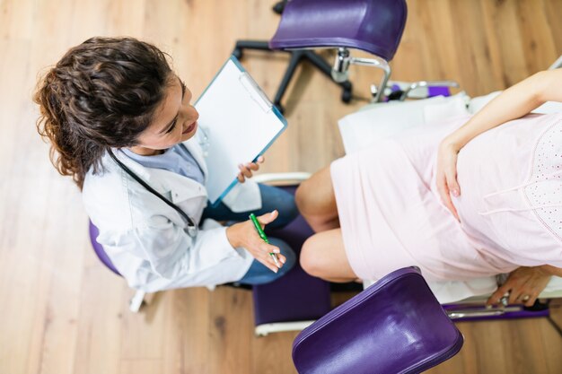 Beautiful young pregnant woman in gynecological chair during gynecological exam.