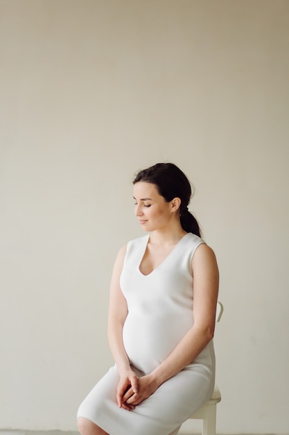 Beautiful young pregnant woman posing in studio in dress