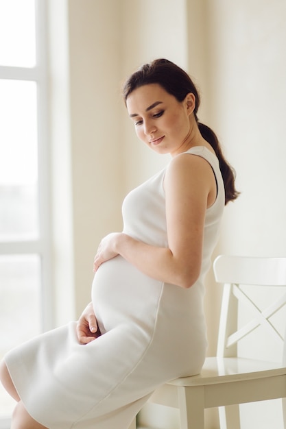 Beautiful young pregnant woman posing in studio in dress