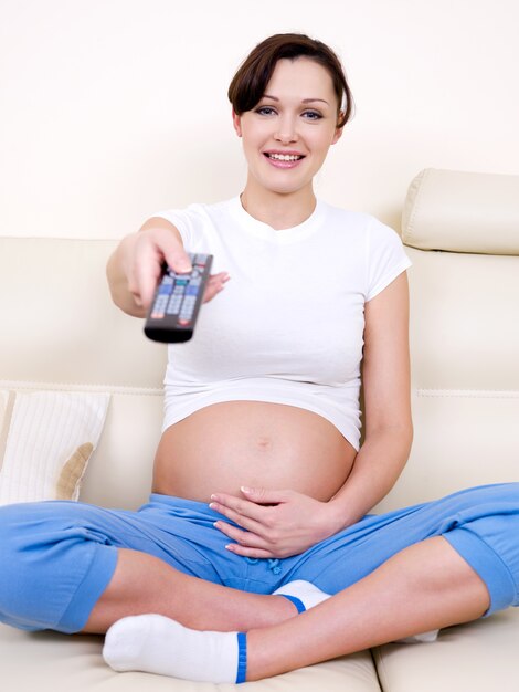 Beautiful young pregnant woman pregnant woman watching tv