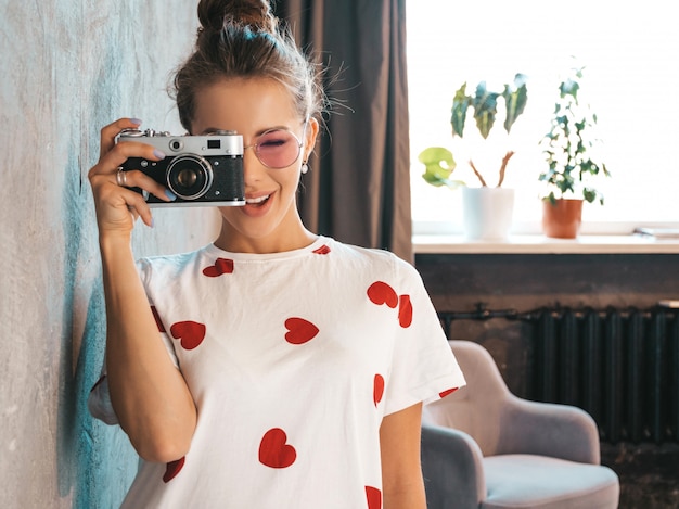 Beautiful young smiling photographer girl taking photos using her retro camera  Woman making pictures 