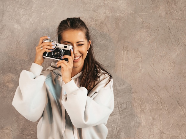 Beautiful young smiling photographer girl taking photos using her retro camera.