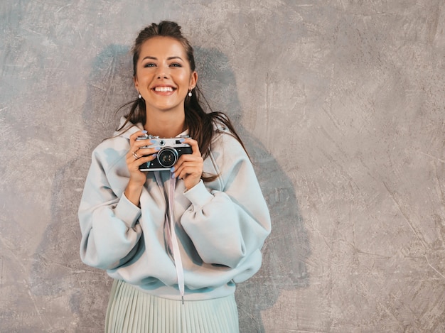 Beautiful young smiling photographer girl taking photos using her retro camera. 