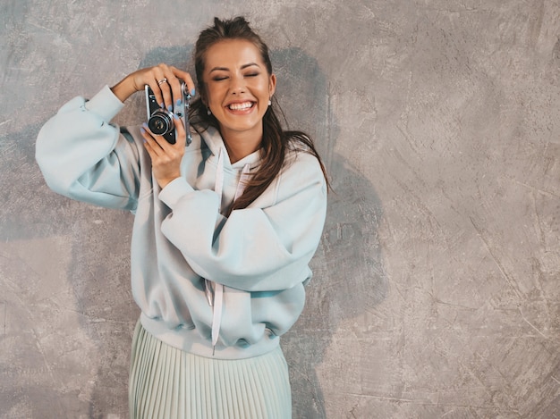 Beautiful young smiling photographer girl taking photos using her retro camera. 