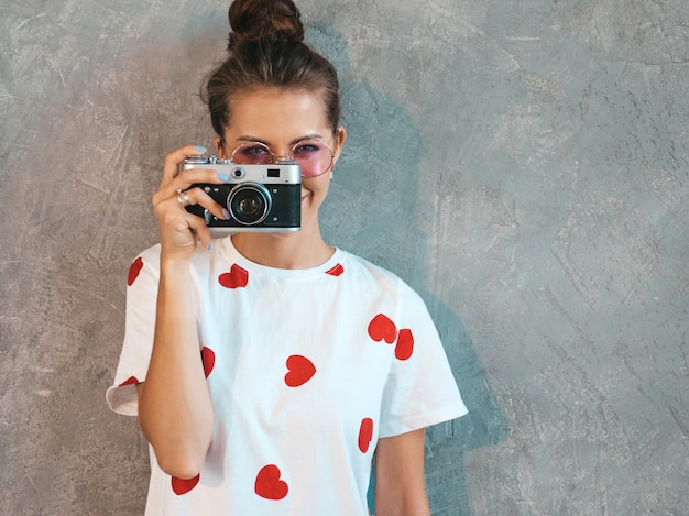 Beautiful young smiling photographer girl taking photos using her retro camera. 