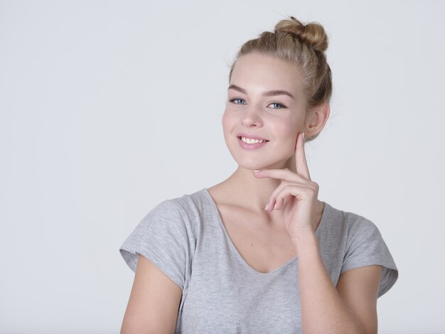 Beautiful young thinking caucasian woman with finger near face  isolated on white background