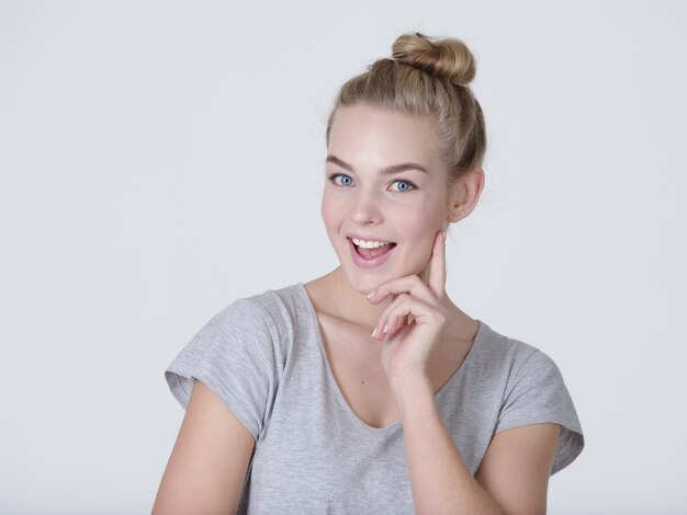 Beautiful young thinking caucasian woman with finger near face  isolated on white background