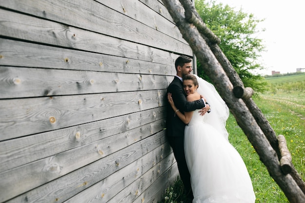 Красивая молодая свадебная пара стоит возле старого деревянного дома