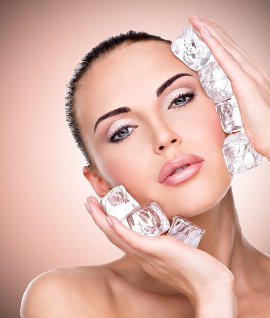 Beautiful young woman applies the ice to face.