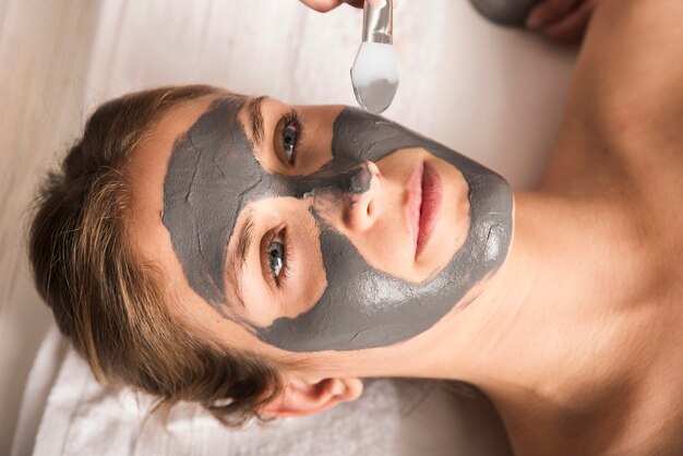 Beautiful young woman applying face mask on her face