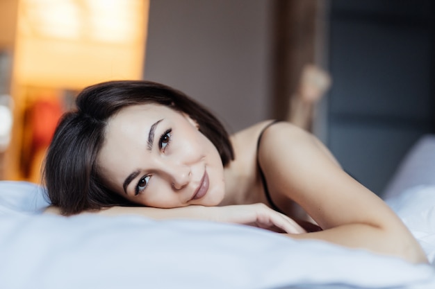 Beautiful young woman in bed in the early morning