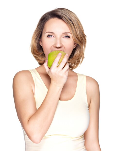 Beautiful young woman biting the biting a fresh ripe apple on white.