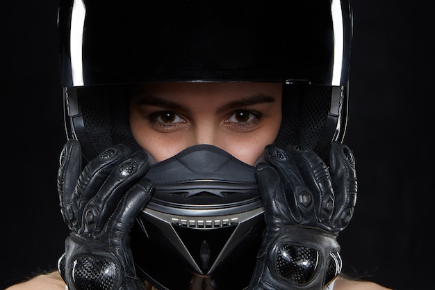 Beautiful young woman in black leather gloves and protective motorbike helmet. Attractive self determined female motocycle racer wearing hands and body protection from falls and accidents