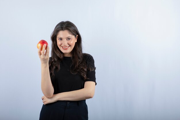 beautiful young woman in black top holding fresh apple. 