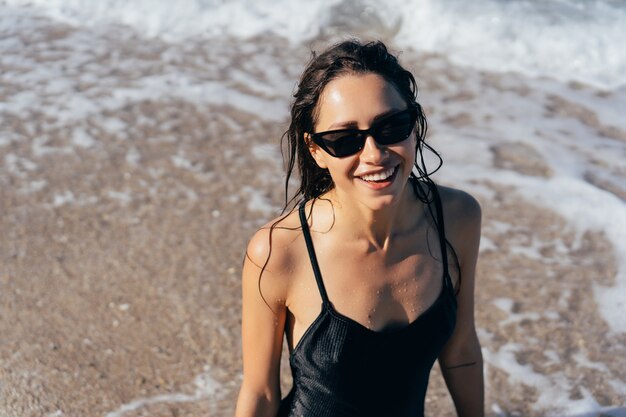 Beautiful young woman in black wet swimsuit