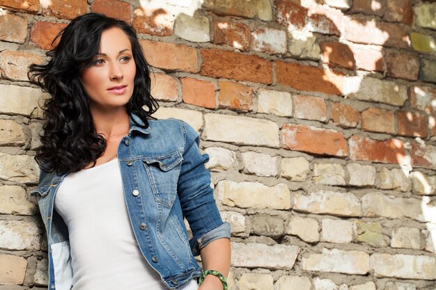 Beautiful young woman at the brick wall