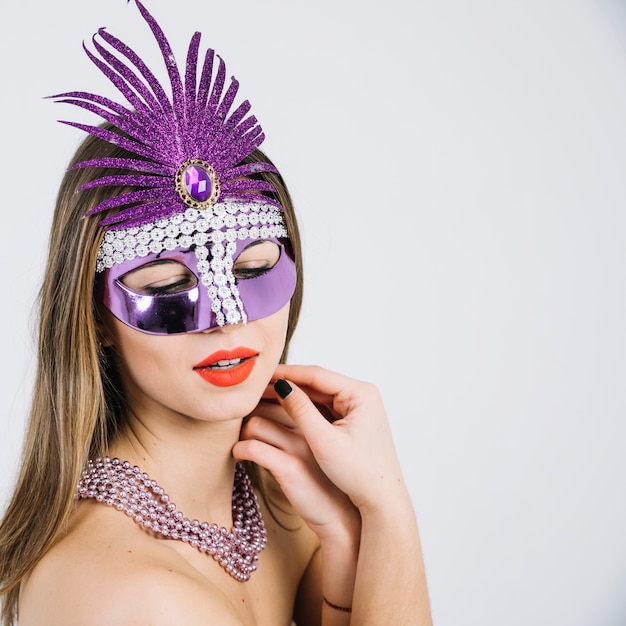 Beautiful young woman in carnival mask posing on white backdrop