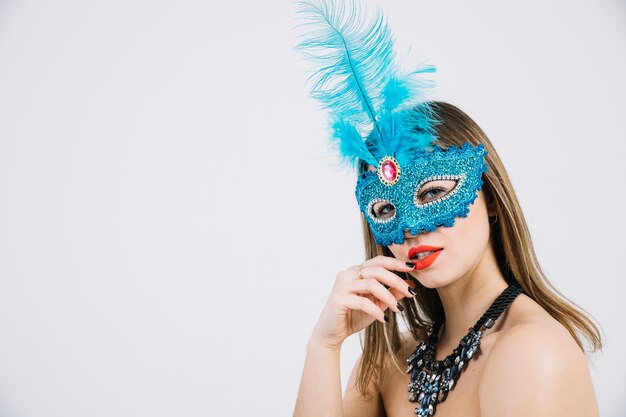Beautiful young woman in carnival mask posing on white backdrop
