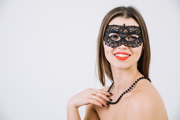 Beautiful young woman in carnival mask and on white background