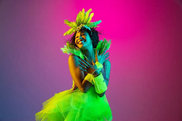 Красивая молодая женщина в карнавальном и маскарадном костюме на градиенте в неоновом свете