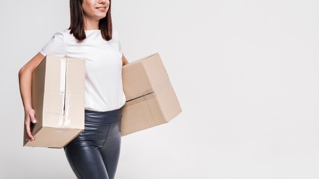 Beautiful young woman carrying cardboard boxes