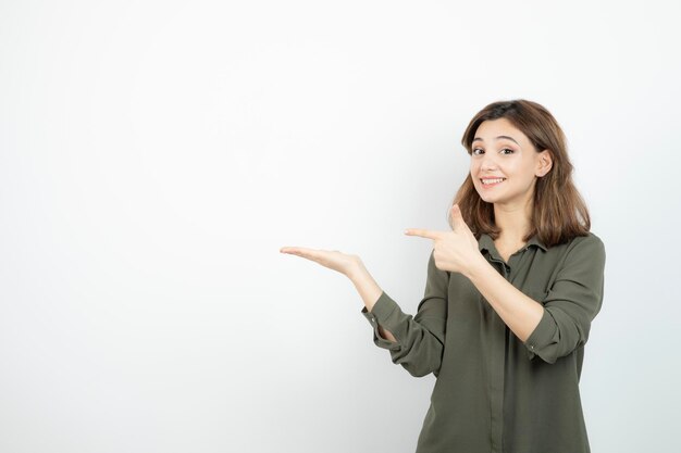 彼女の開いた手のひらを示すカジュアルな服装の美しい若い女性。高品質の写真