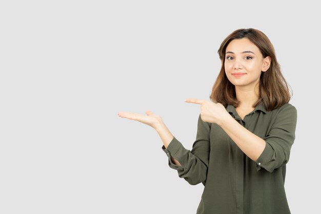 彼女の開いた手のひらを示すカジュアルな服装の美しい若い女性