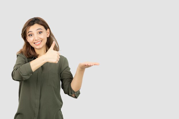 彼女の開いた手のひらを示すカジュアルな服装の美しい若い女性