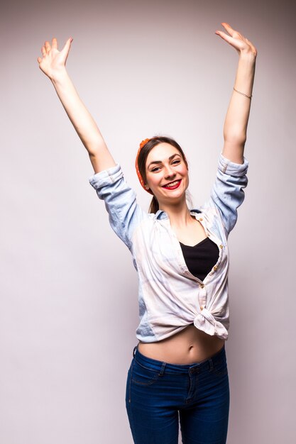 Beautiful young woman in casual wear raising arm over white