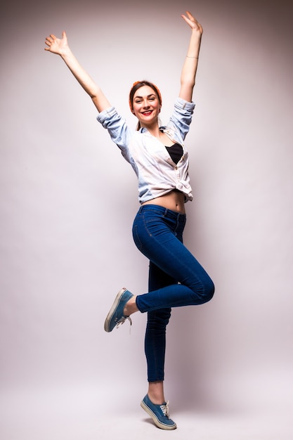 Foto gratuita bella giovane donna in abbigliamento casual che alza il braccio sopra bianco