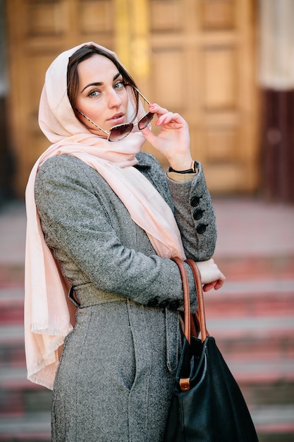 Foto gratuita bella giovane donna in un cappotto con una borsa in posa