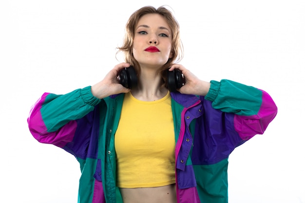 Beautiful young woman in colorful jacket and holding headphones