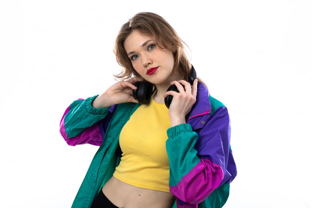 Beautiful young woman in colorful jacket and holding headphones