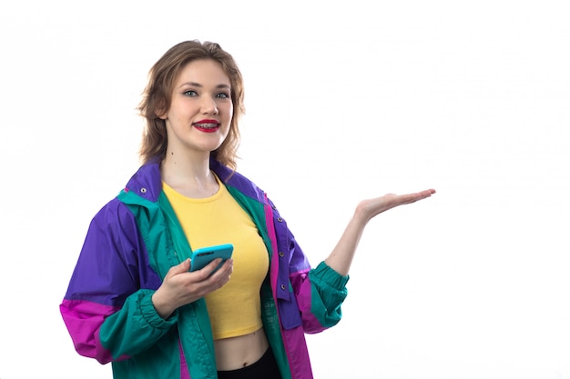 Free photo beautiful young woman in colorful jacket using smartphone and holding something