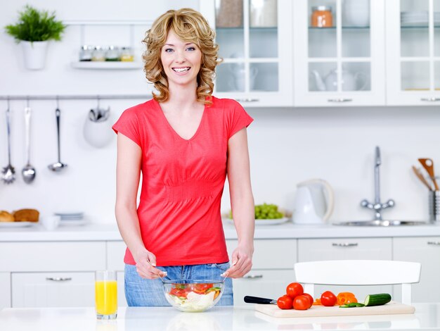 Beautiful young woman cooking healthy food in the kitchen - indoors