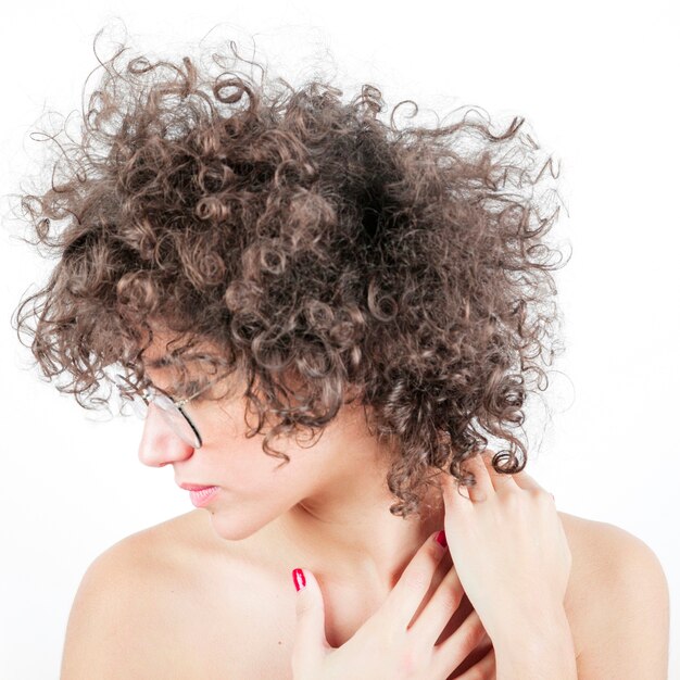 Beautiful young woman in curly hair wearing spectacles against white background