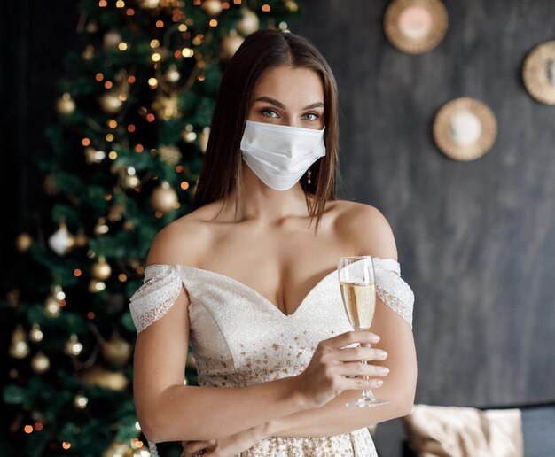 beautiful young woman in dress in mask and champagne