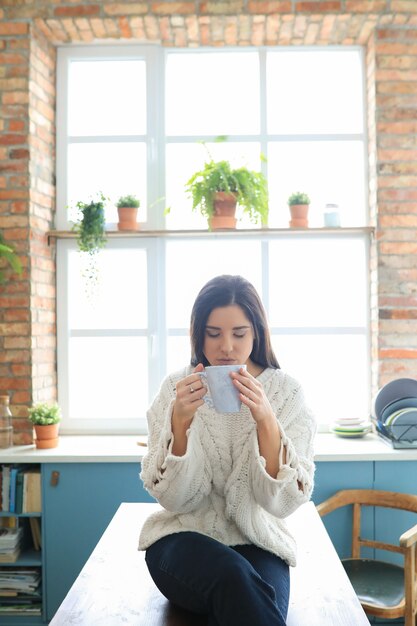 부엌에서 뜨거운 음료를 마시는 아름 다운 젊은 여자