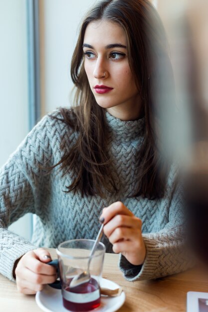 Beautiful young woman drinking tea in a coffee shop.