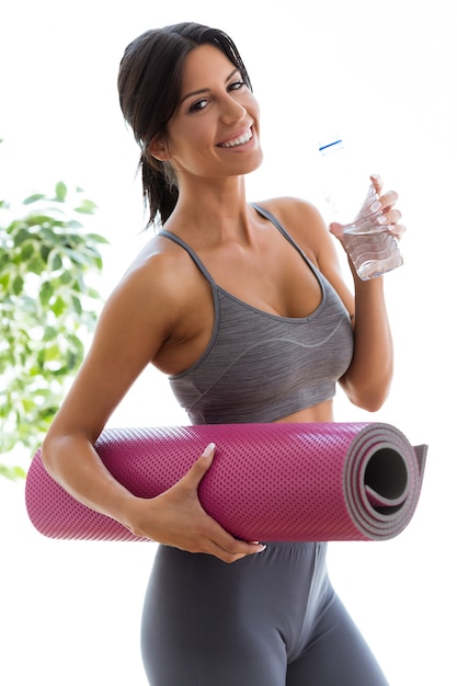 Free photo beautiful young woman drinking water after a workout at home.