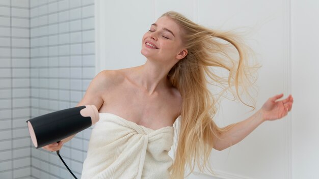 Beautiful young woman drying her hair