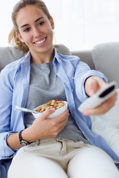 Beautiful young woman eating cereals at home.