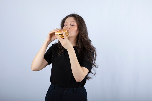 Beautiful young woman eating delicious beef burger. 