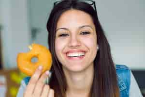 Foto gratuita bella giovane donna mangiare ciambelle a casa.